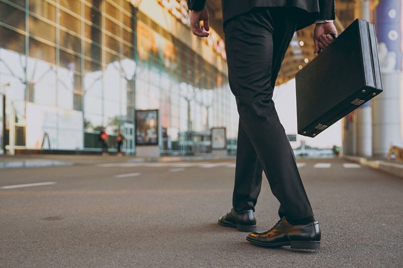 A man in a suit holding a briefcase walks to deliver a business pitch