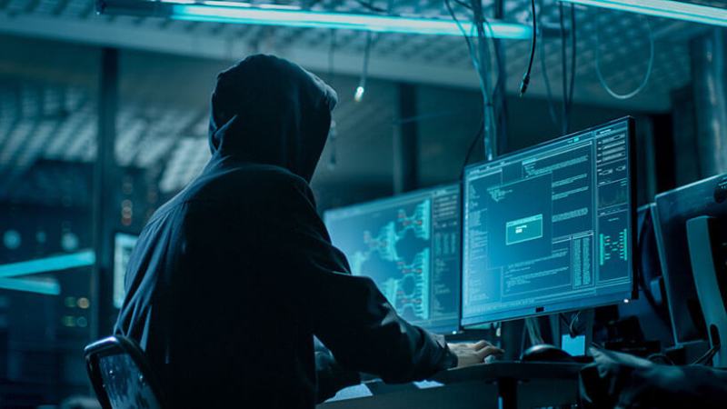 Hooded hacker breaking into corporate data servers.