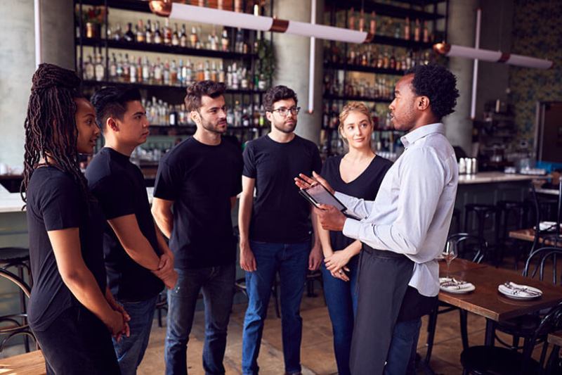 Manager talks to employees in a team meeting in a pub