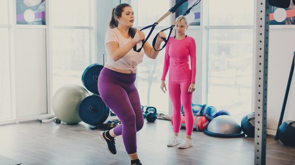 Fitness instructor helping a client in the gym with thier personal program