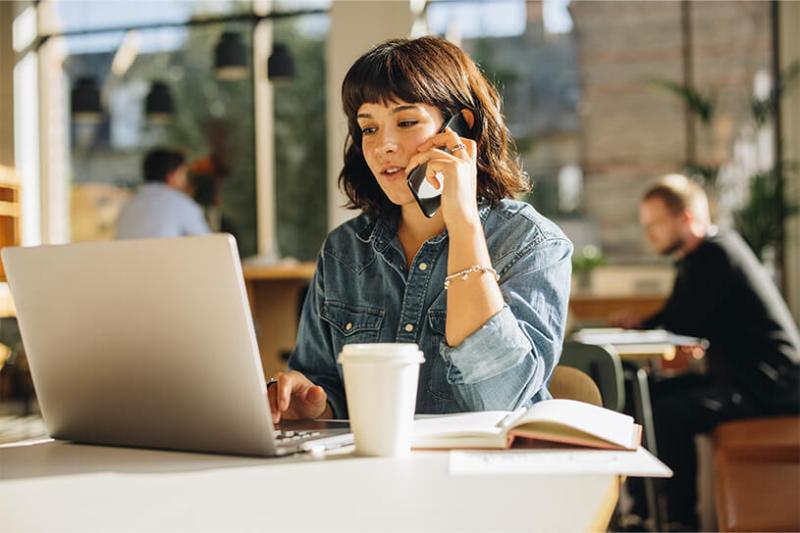 Freelancer on the phone and laptop, drinking a coffee