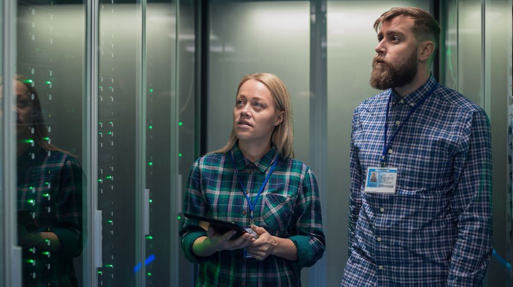 Male and female software professionals looking at a server