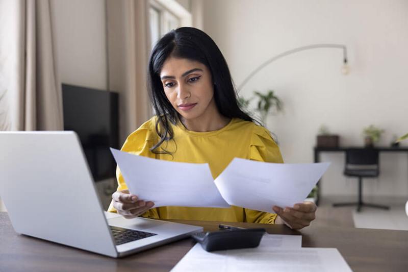 Woman looking at receipts in order to digitally submit her income tax report on a laptop