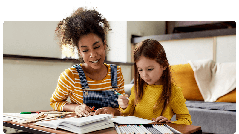 A childminder helping a little girl with her homework.