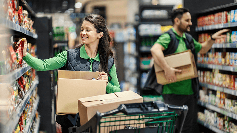 Two supermarket assistants stacking the shelves